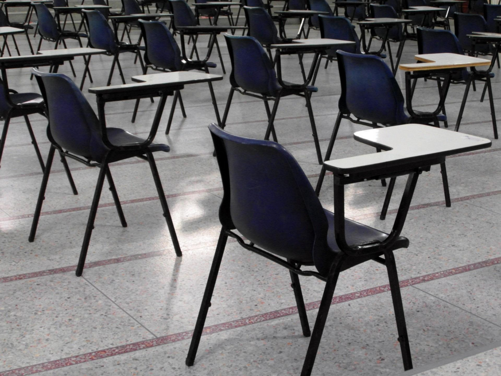 Salle d'examen vide avec rangées de tables et chaises, illustrant la peur de l'échec examen et le stress du jour J avant une épreuve importante.