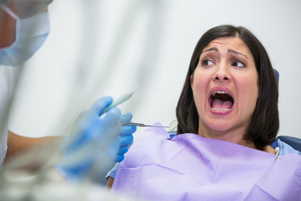 Femme effrayé sur le siège du dentiste, bouche grande ouverte, criant face à la douleur, honte, perte de contrôle et comment l'hypnose peut aider à les dépasser.