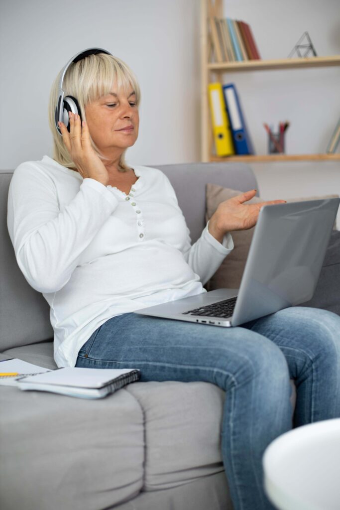 Femme installée confortablement chez elle avec un casque, prête pour une séance d'hypnose en visioconférence