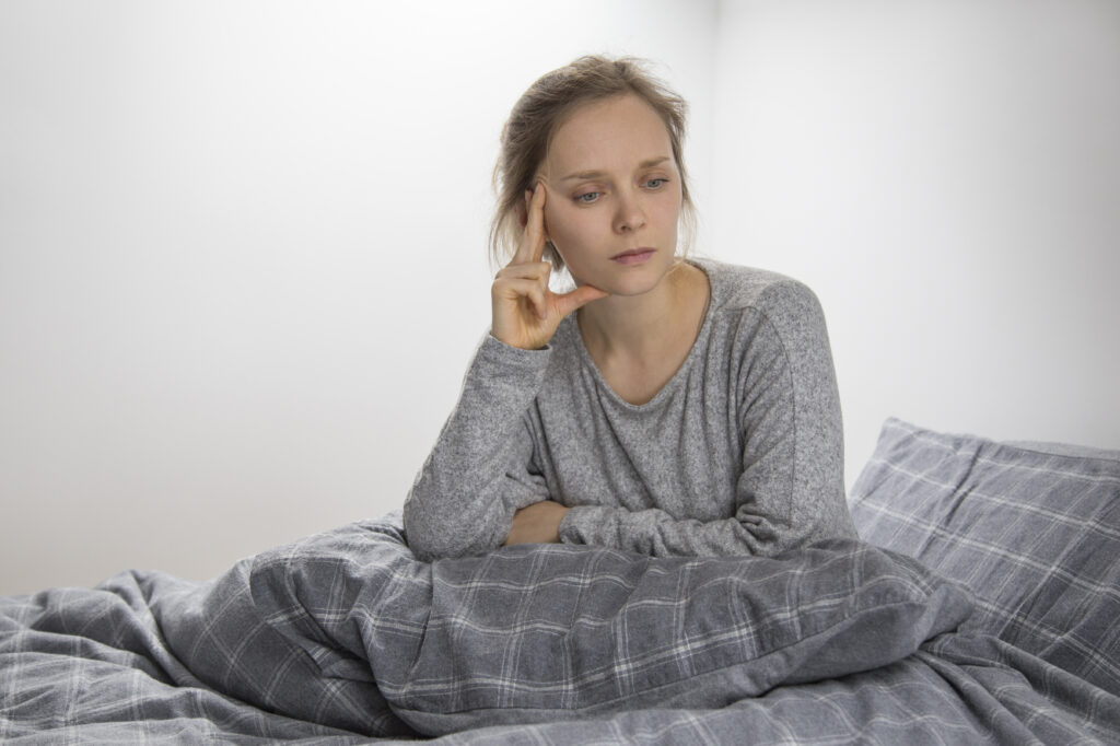 Personne assise da,s son lit le matin, ressentant une anxiété au réveil.