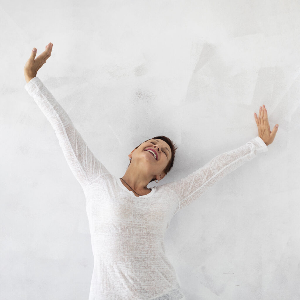Femme célébrant une réussite, bras levés en l'air, illustrant l'importance de célébrer les petites victoires, symbolisant la confiance en soi retrouvée